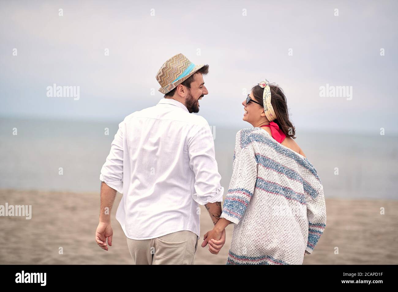 image de jeune couple adulte mignon à la plage, tenant les mains, regardant les uns les autres, riant Banque D'Images