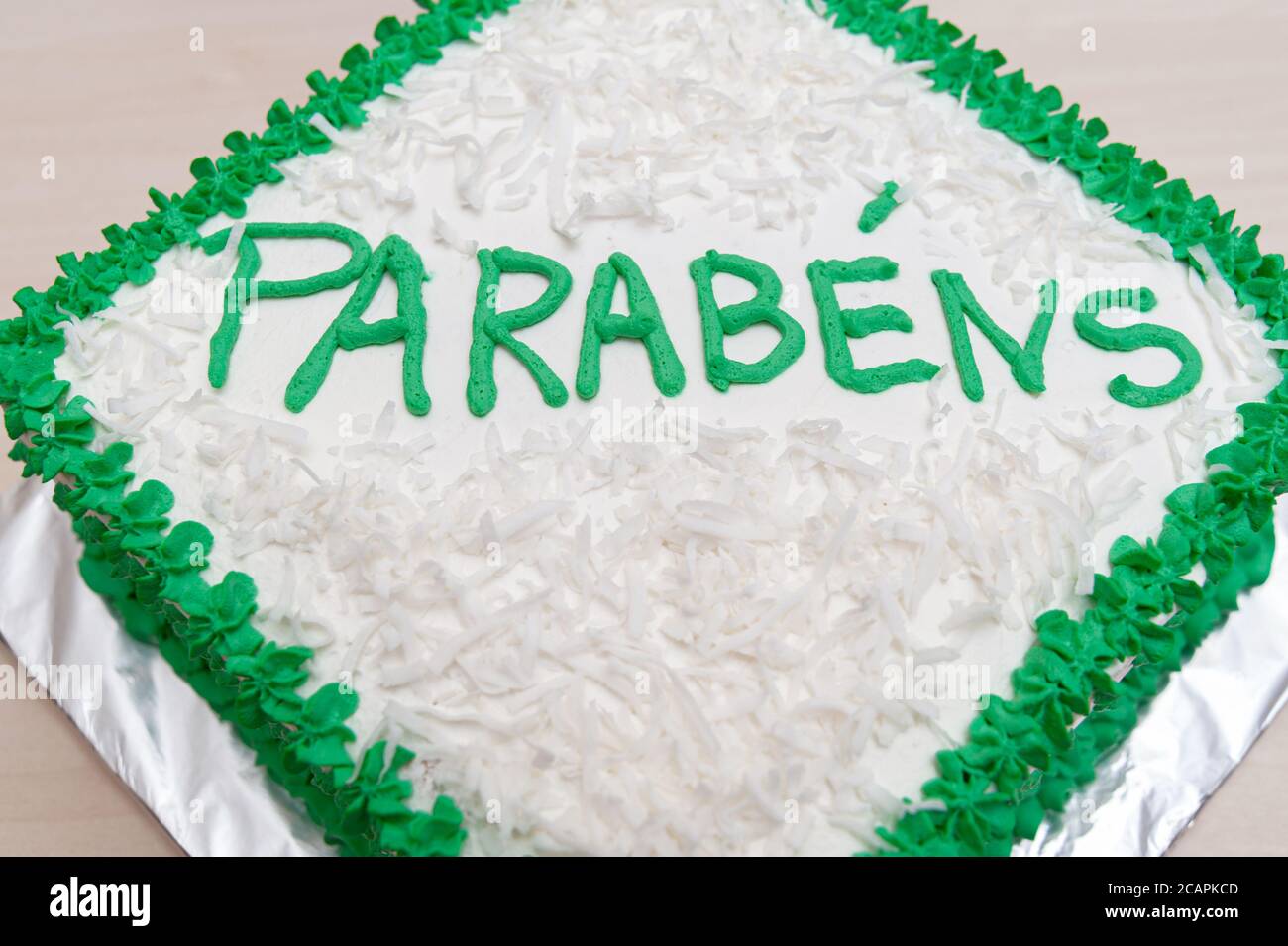 Gâteau d'anniversaire décoré de glace verte et de noix de coco râpée. Isolé sur fond de table en bois. Vue de dessus. Gros plan. Banque D'Images