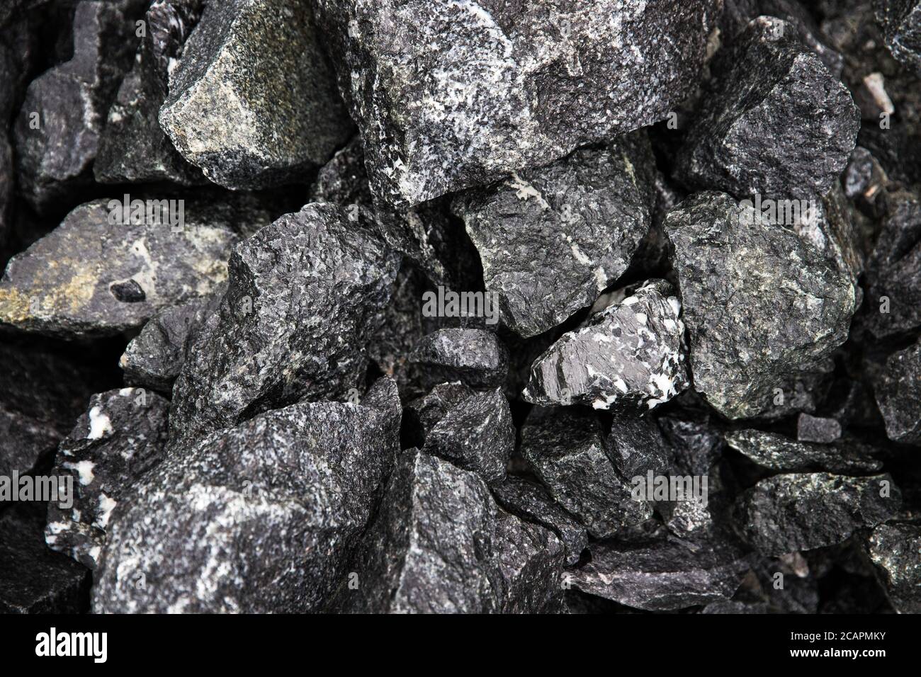 Fragments de pierres noirs naturels humides avec billes perlées pour les arrière-plans, vue du dessus. Gros morceaux de pierre cassés. Tas de pierres humides noires Banque D'Images