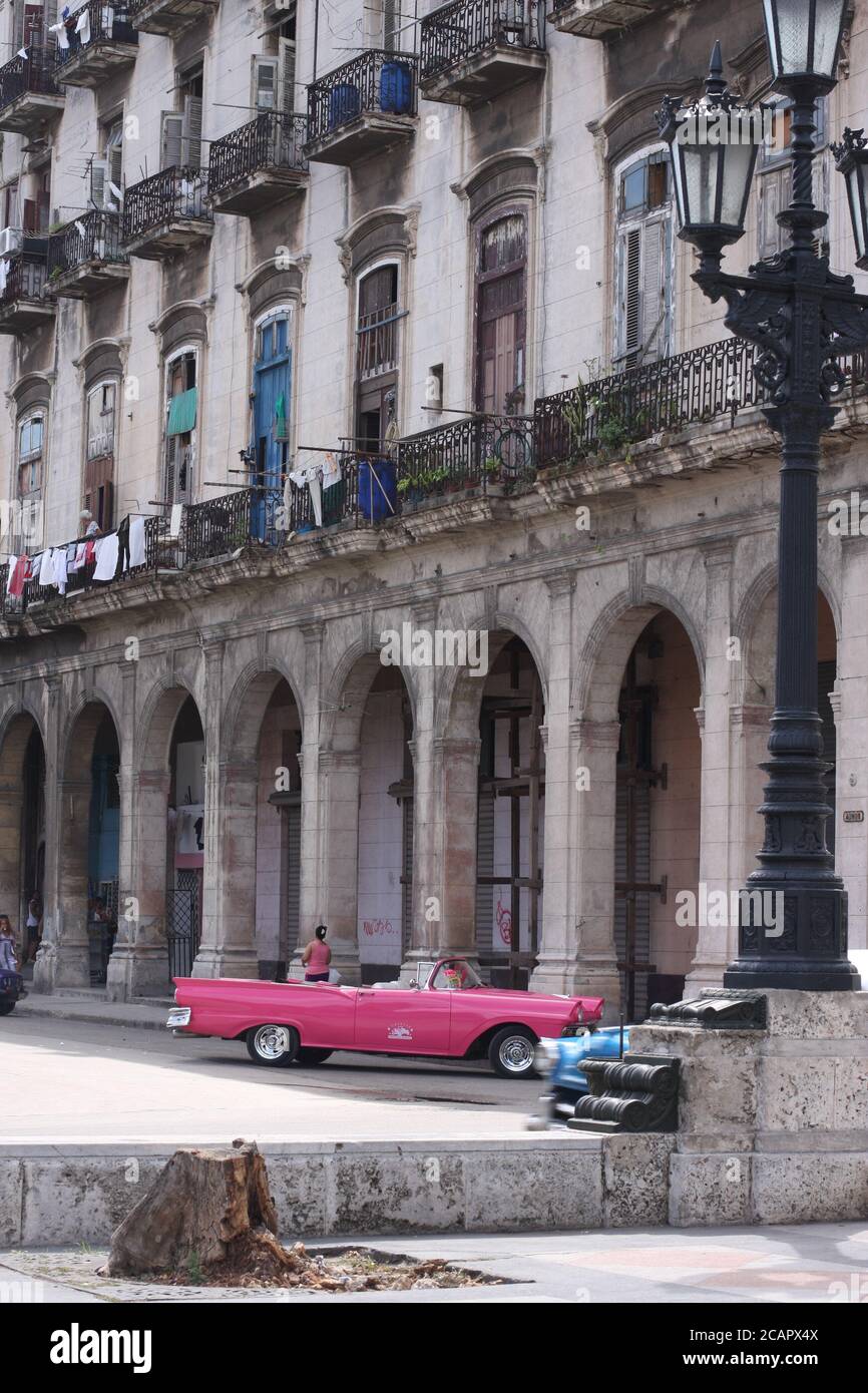 Scène de rue à la Havane, Cuba, avec voiture d'époque rose garée et lavage accroché à un bâtiment de style colonial Banque D'Images