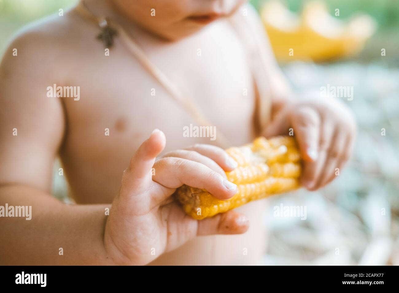 Les mains du petit garçon mangeant du maïs en gros plan Banque D'Images