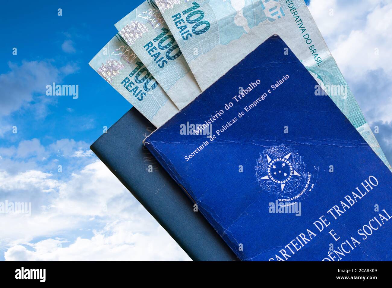 Carte de travail brésilienne avec argent brésilien isolé sur fond bleu ciel et nuages. Écrit en République fédérative portugaise du Brésil, Ministère de Banque D'Images