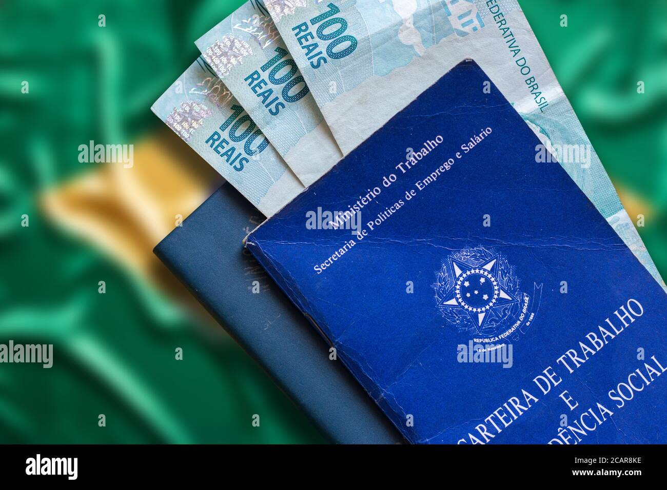 Carte de travail brésilienne avec argent brésilien isolé sur fond défoqué de drapeau brésilien. Écrit en République fédérative portugaise du Brésil, Ministr Banque D'Images