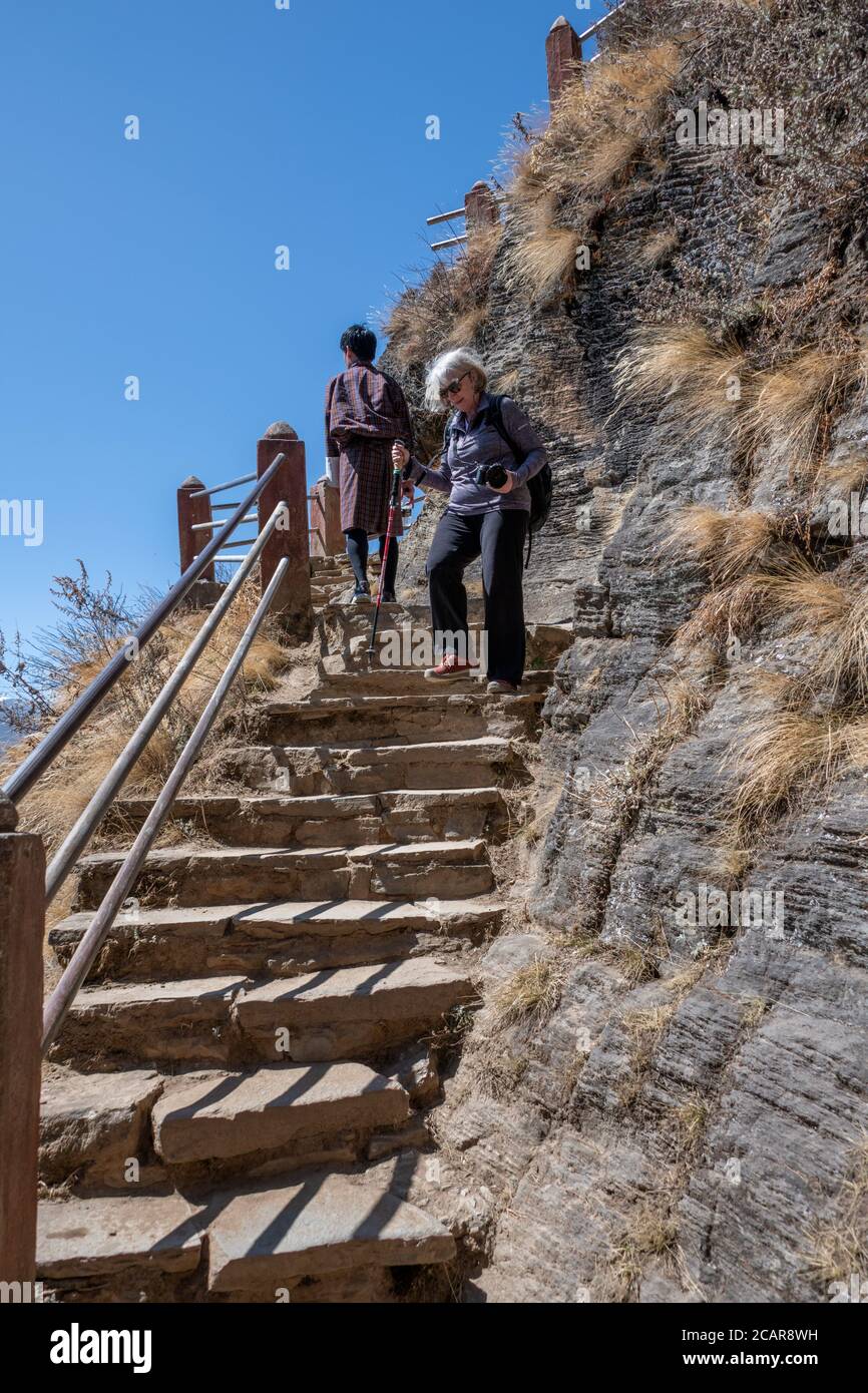 Bhoutan, Paro. Taktshang Goemba ou le monastère Tiger’s Nest, l’un des sites religieux les plus sacrés du Bhoutan. Sentier de randonnée de haute altitude, touristique féminine. Banque D'Images