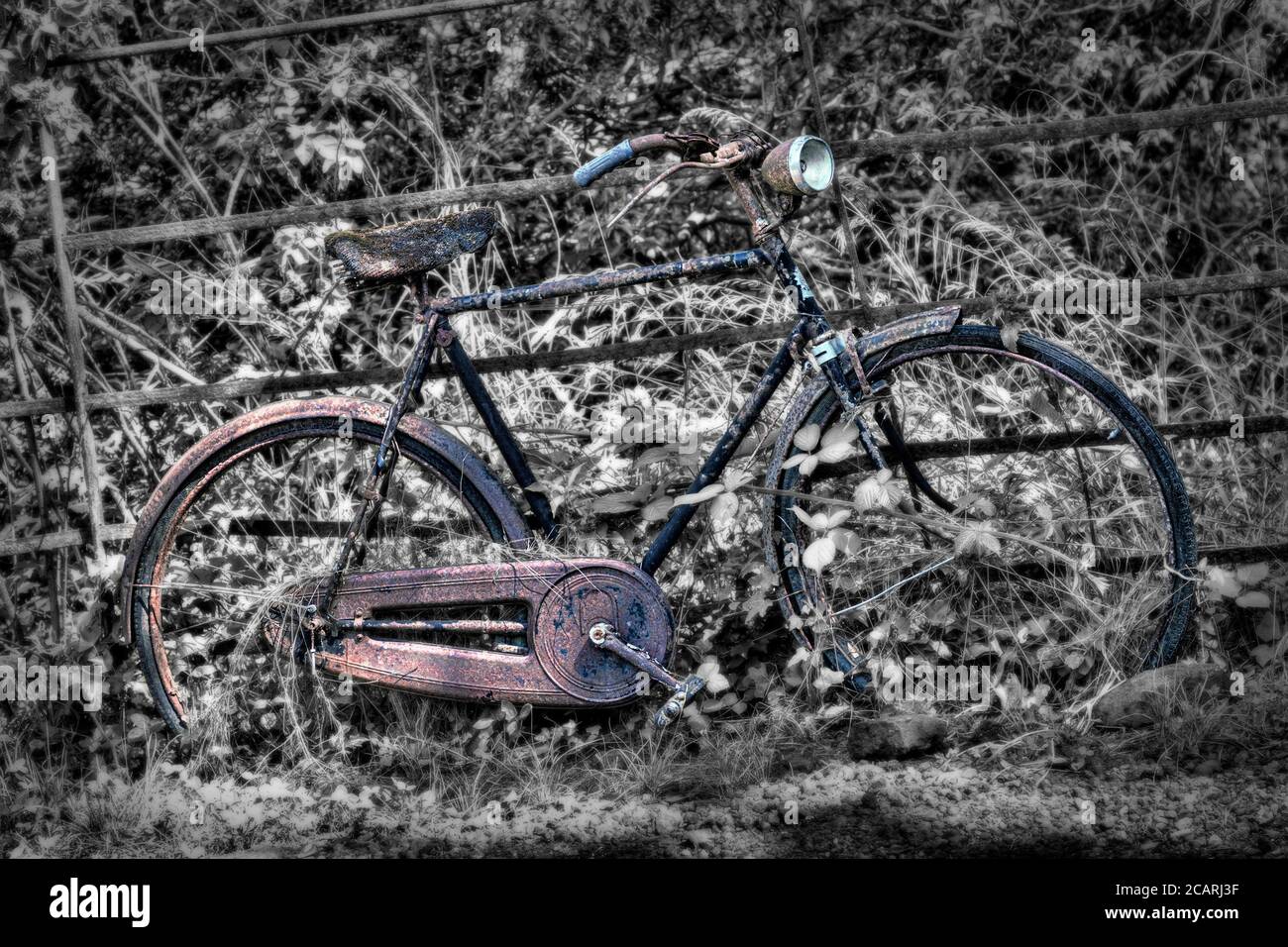 ancienne bicyclette abandonnée penchée contre la clôture avec effet désaturé Banque D'Images