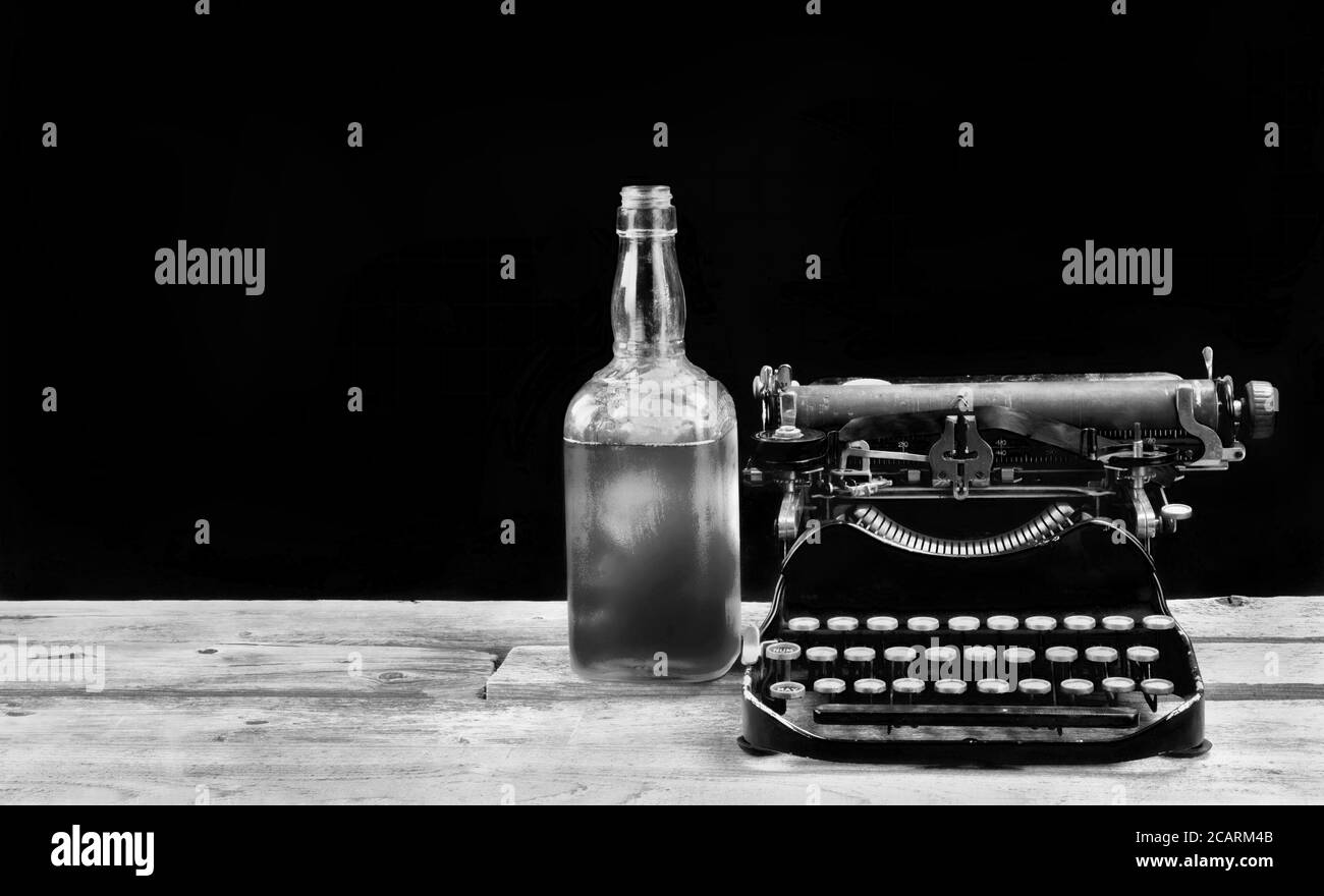 Machine à écrire portative antique fabriquée en 1917 avec bouteille de whisky et espace pour votre type en noir et blanc. Banque D'Images