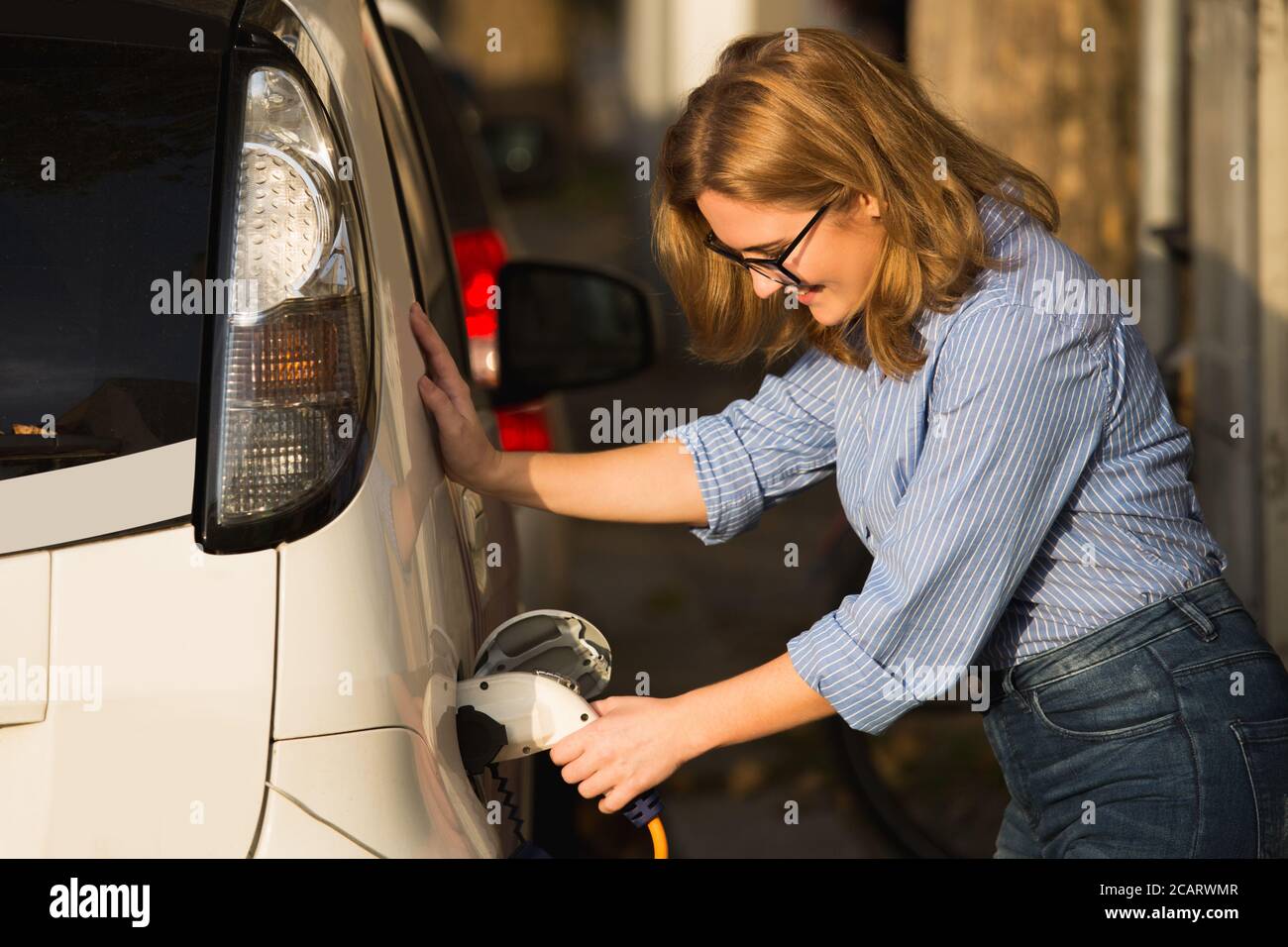 La femme charge la voiture électrique de partage de voiture. Banque D'Images