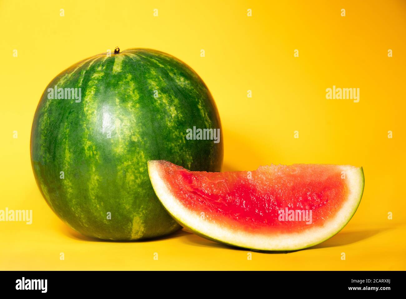 un melon d'eau entier et une tranche de pastèque sans graines sur fond jaune. thème d'été. fraîcheur. Délicieux melon d'eau mûr, juteux et rafraîchissant. Sucreries d'août. Banque D'Images