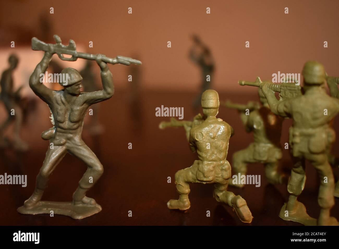 Un soldat de jouet charge un groupe d'autres soldats de jouet Sur une surface en bois Banque D'Images