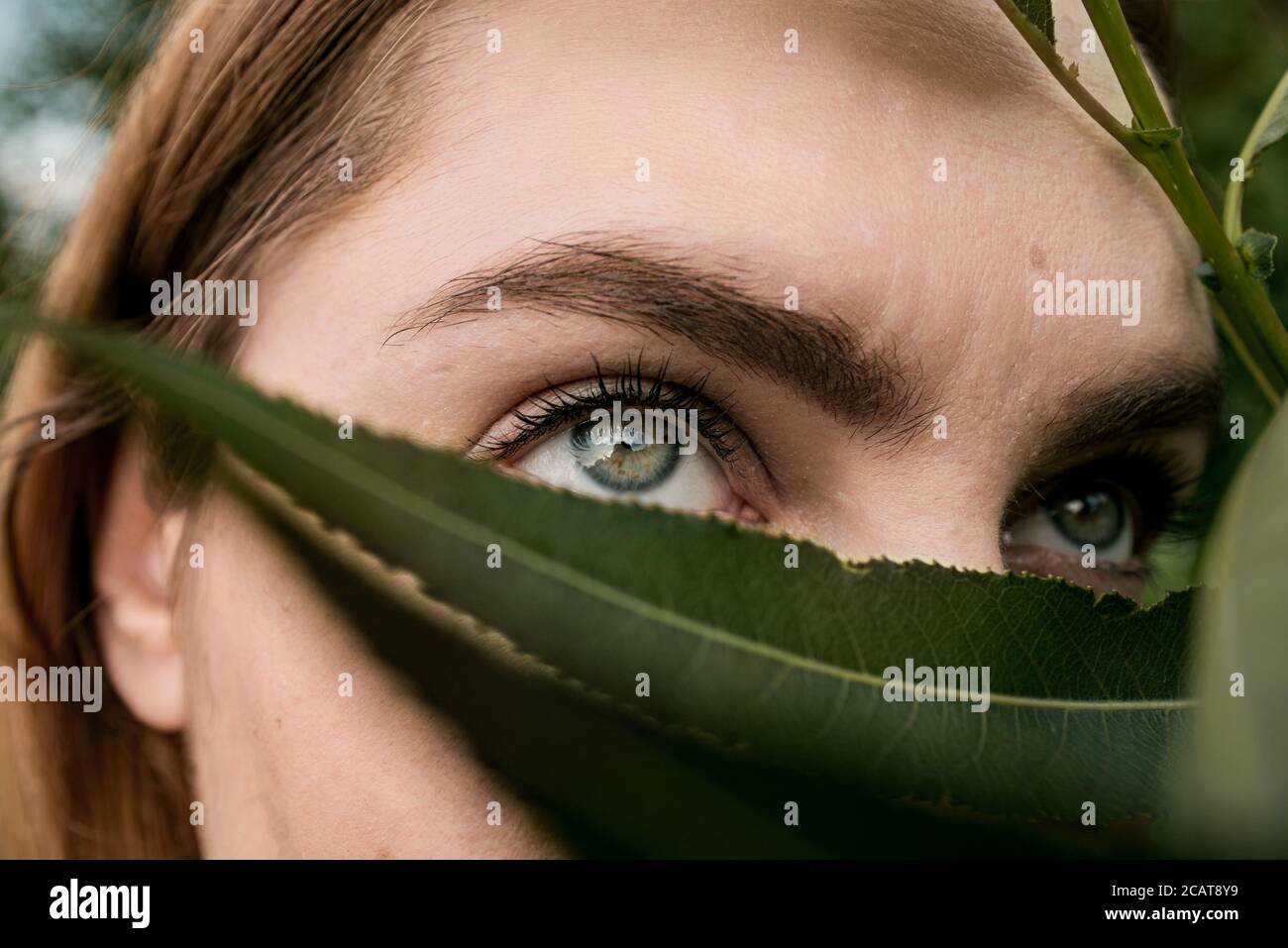 femme yeux couverts de feuille dans la nature concept de masque covid-19 Banque D'Images