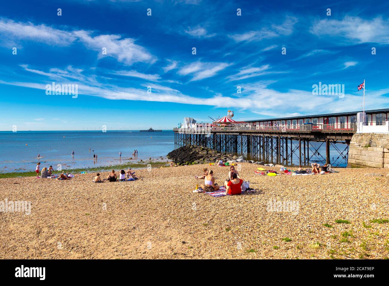 Personnes assises sur la plage près de Herne Bay Pier à Herne Bay, Kent, Royaume-Uni Banque D'Images