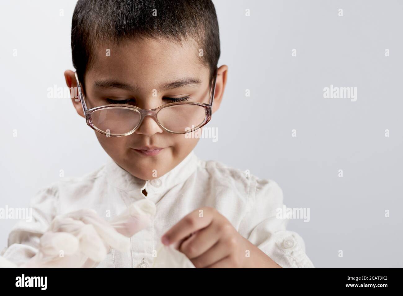 Petit garçon scientifique dans un manteau de laboratoire et lunettes contre le fond blanc Banque D'Images
