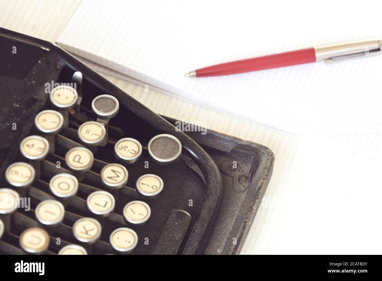 une vieille machine à écrire noire à côté d'une feuille de papier blanche avec un stylo rouge. Outils de journalisme et d'écriture. Narration et activité créative Banque D'Images