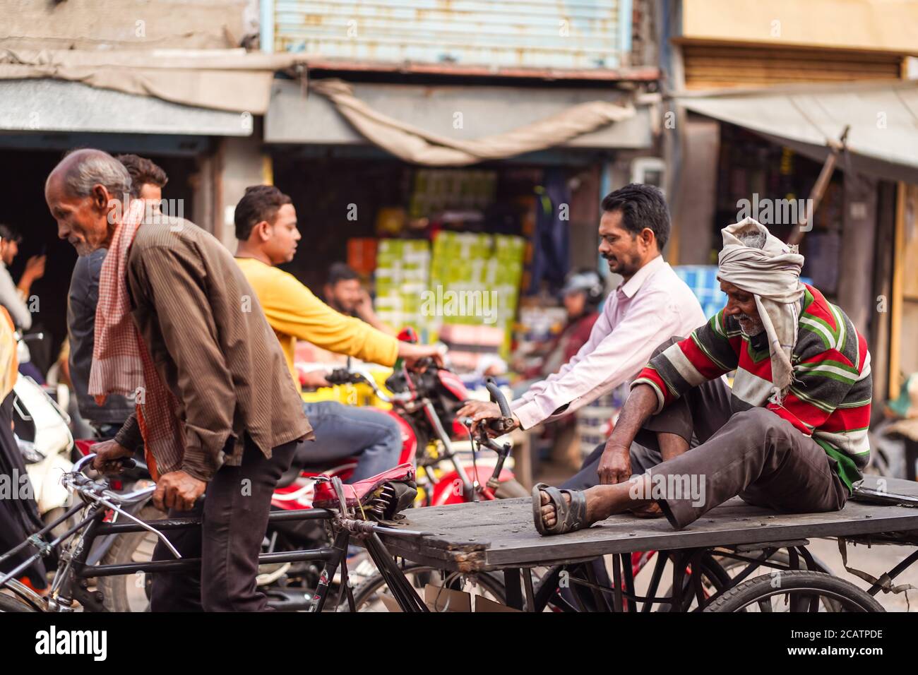 Agra / Inde - 22 février 2020 : ancien indien assis sur la plate-forme d'un tricycle sur la rue historique du centre-ville avec beaucoup de circulation Banque D'Images