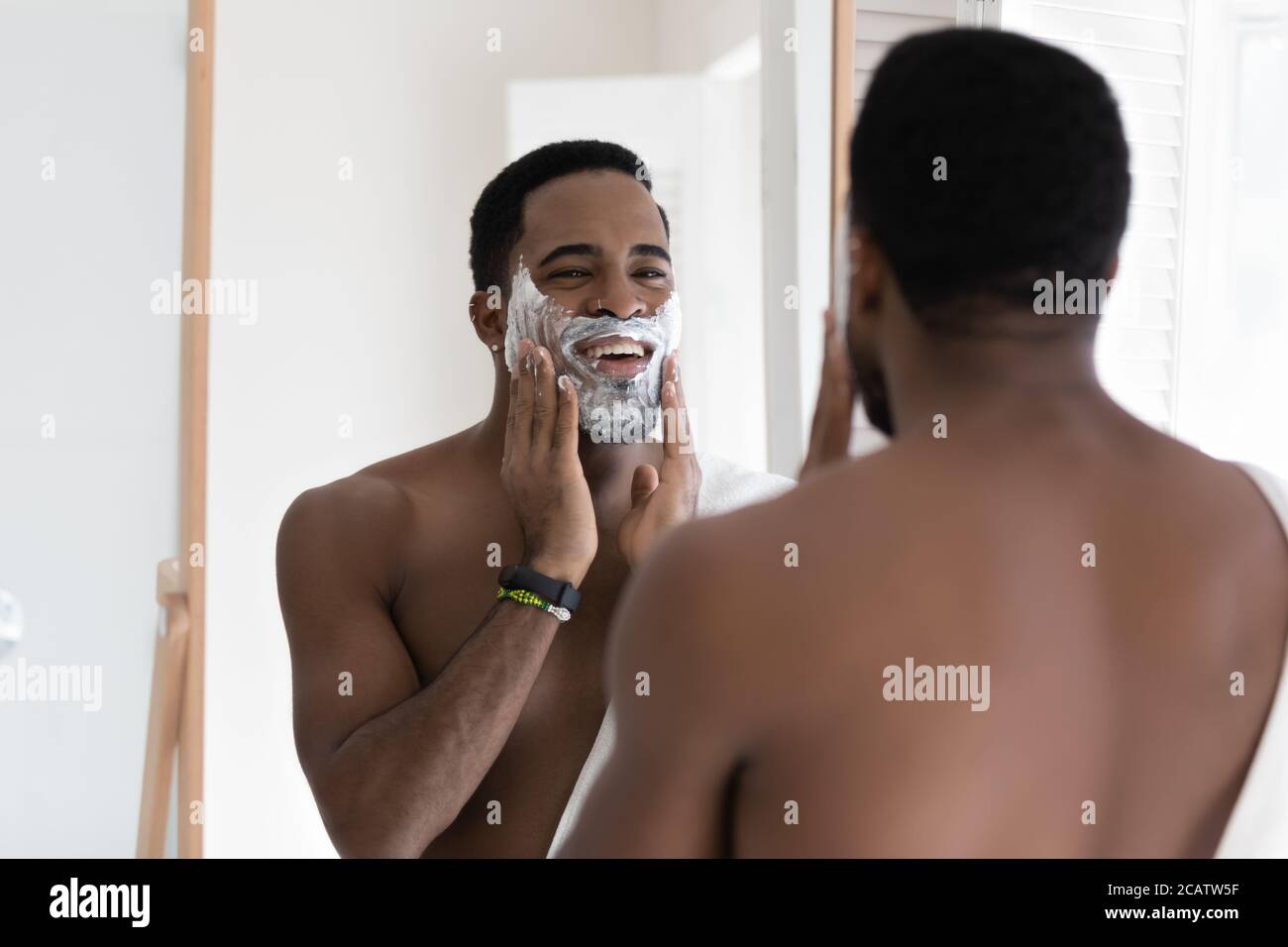 Miroir reflet sourire Afro-américain homme appliquant de la mousse à raser Banque D'Images