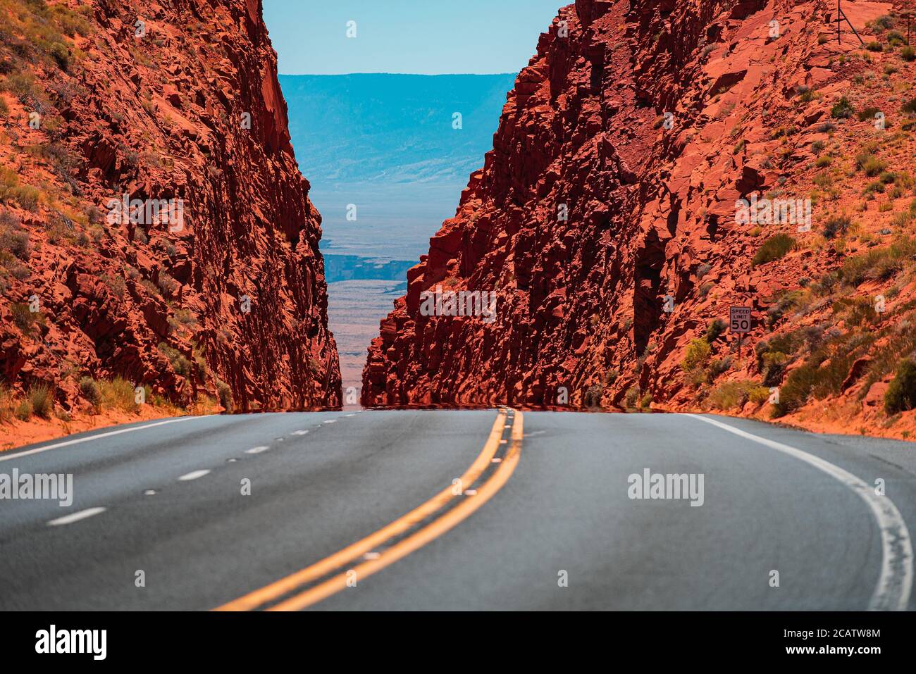 Paysage avec rochers, ciel ensoleillé et route asphaltée. Une longue route droite menant à une montagne rocheuse. Banque D'Images