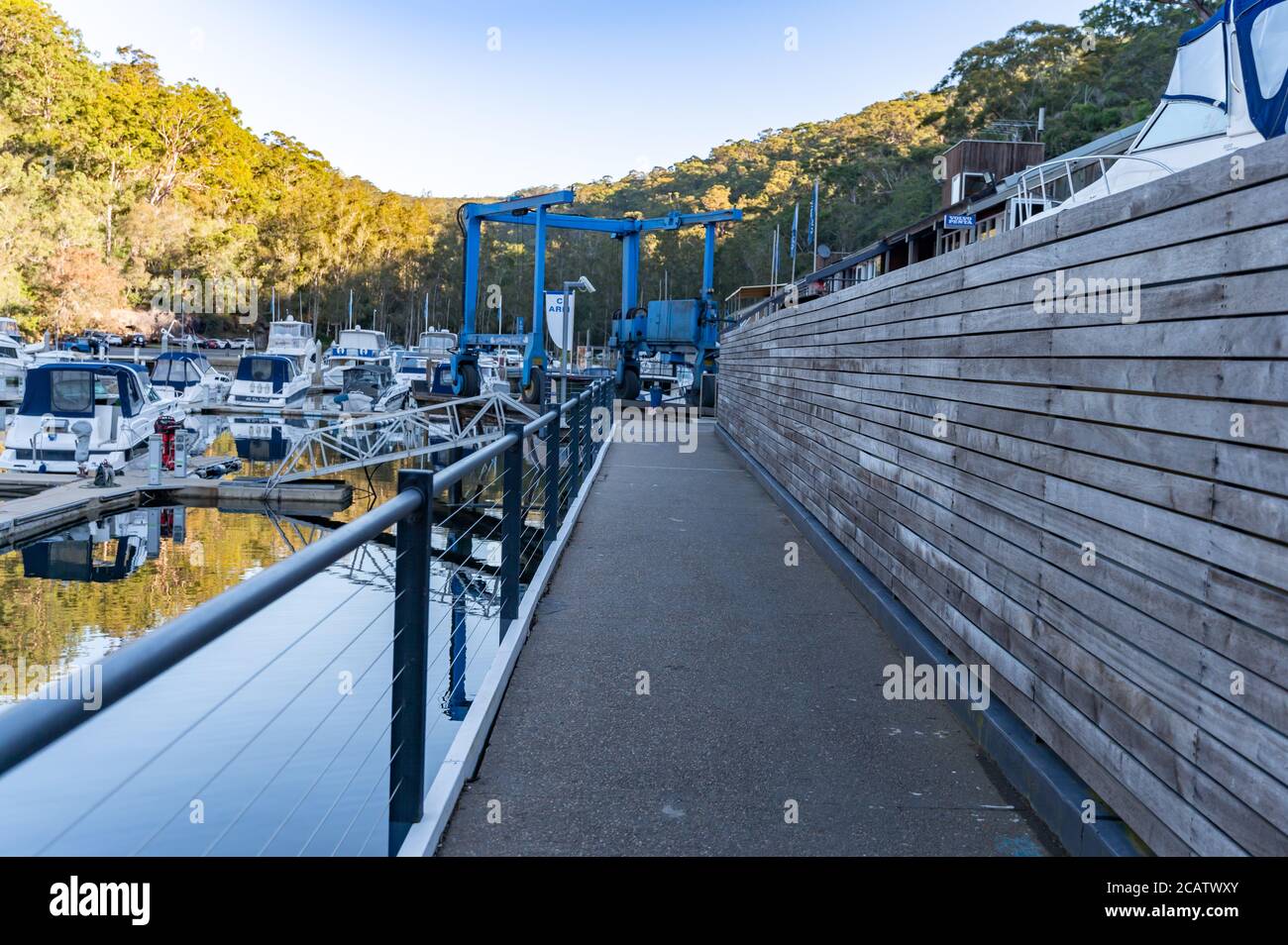 Jetée à la marina d'Akuna Bay avec beaucoup de bateaux amarrés L'arrière-plan du système de lève-bateau est flou sous un hiver ensoleillé après-midi Banque D'Images