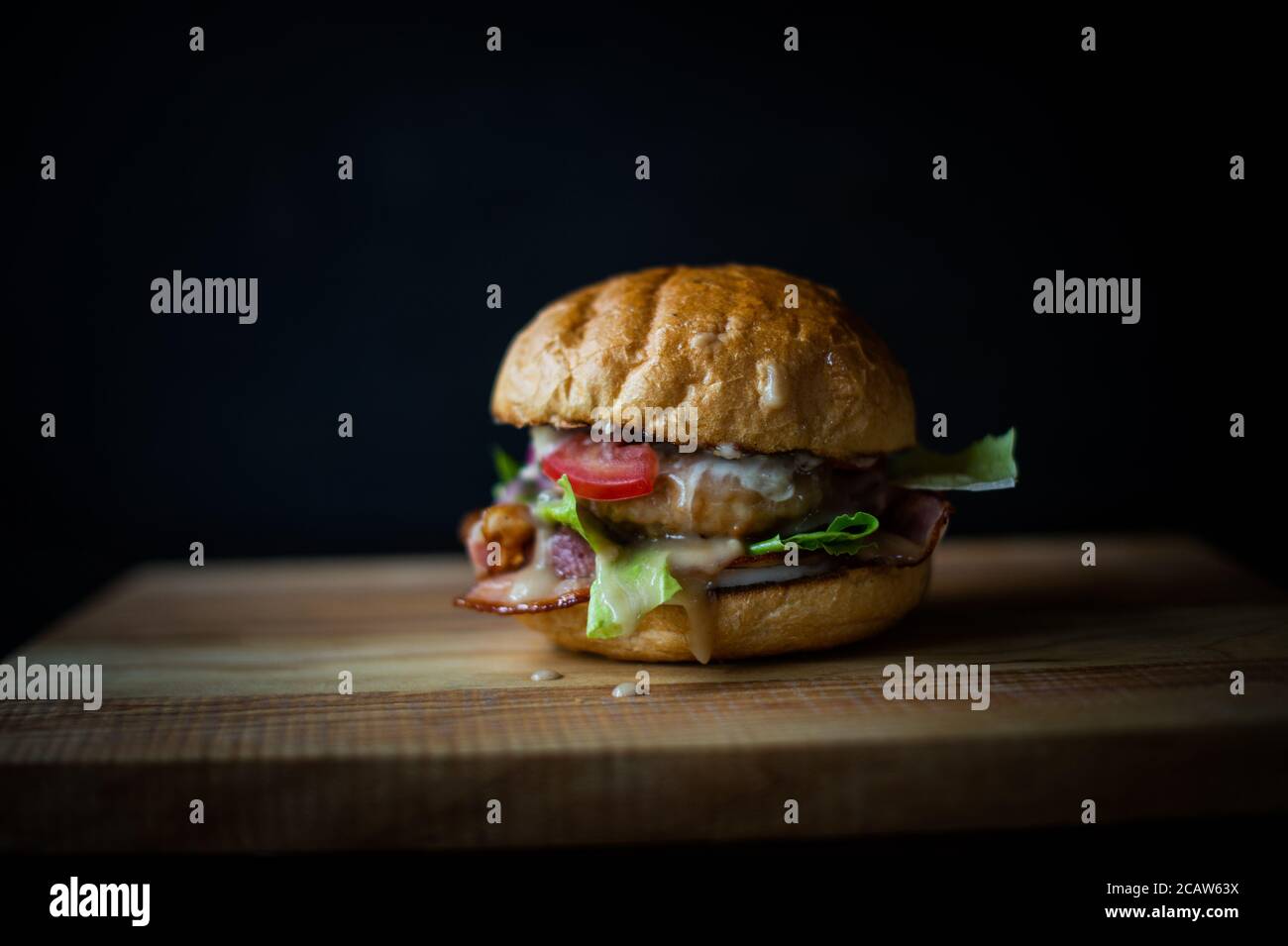 hamburger frais et savoureux sur fond noir. Délicieux hamburger maison frais sur une table en bois Banque D'Images