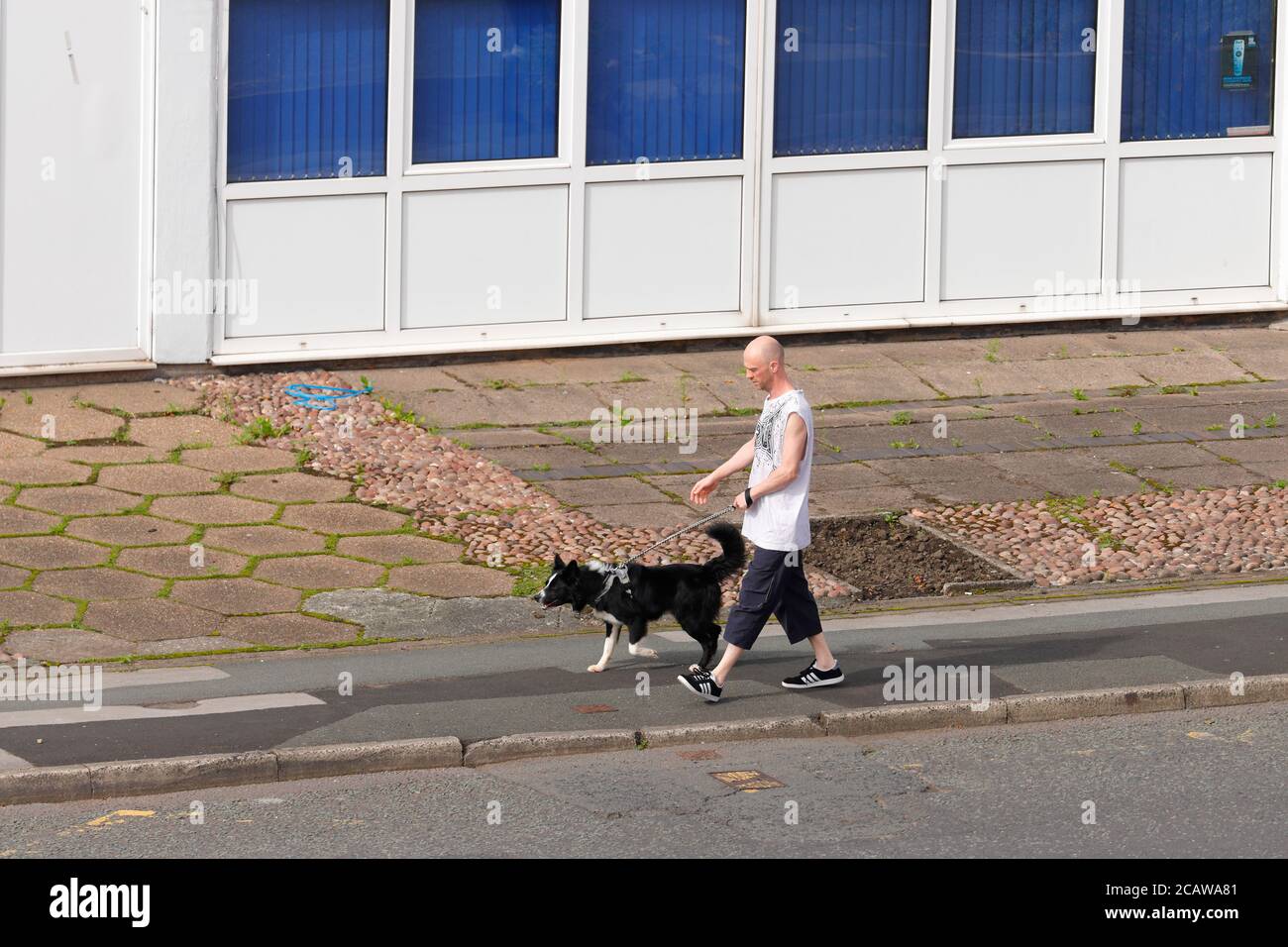 Un homme qui marche un chien à l'extérieur de la gare d'Ambulance Ashton Manchester Banque D'Images