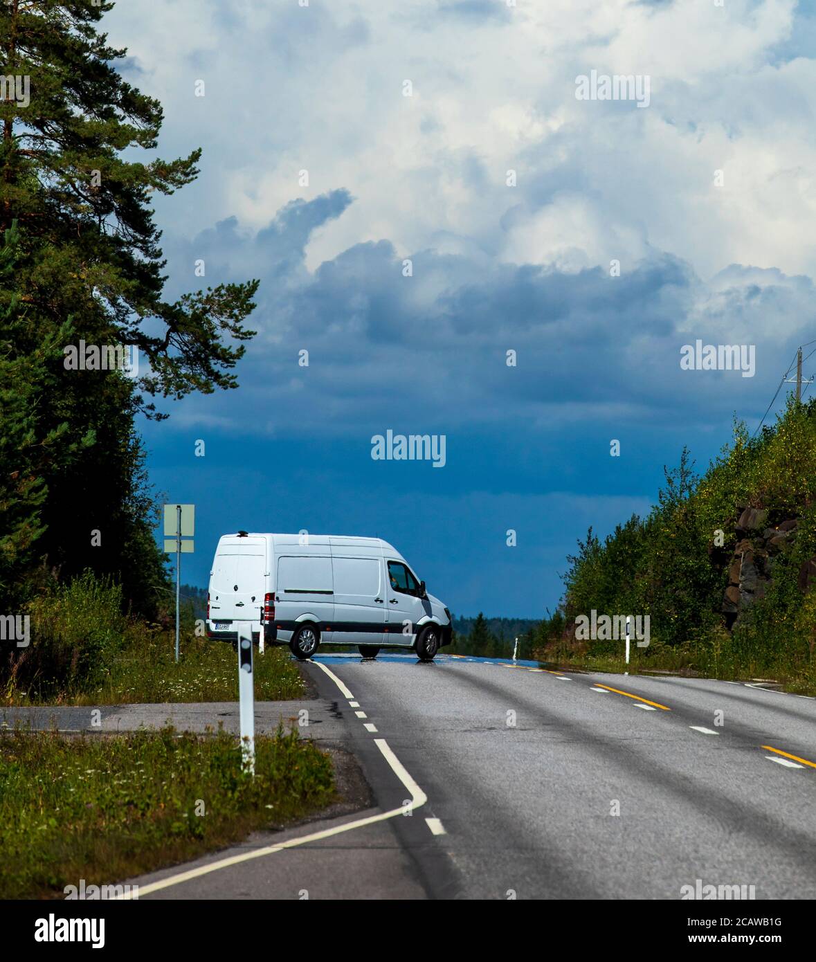 Un minibus blanc tournant sur une autoroute vide à la campagne à été , Finlande Banque D'Images