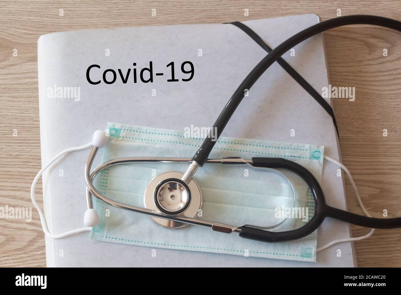 Dossier avec Covid-19 écrit dessus, masque médical et stéthoscope Banque D'Images