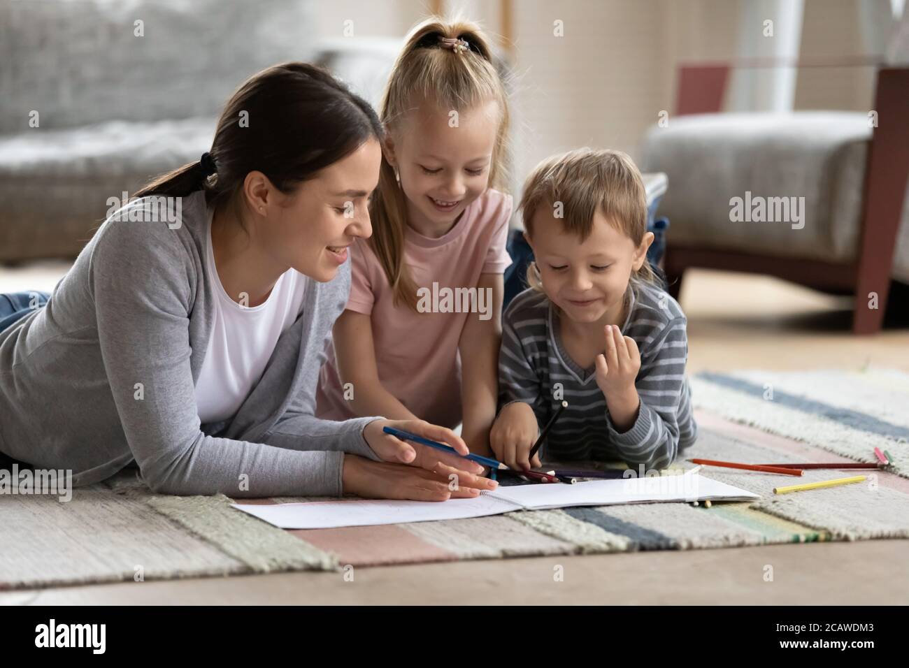 Affectueuse et affectueuse, jeune mère qui aime dessiner avec les enfants. Banque D'Images