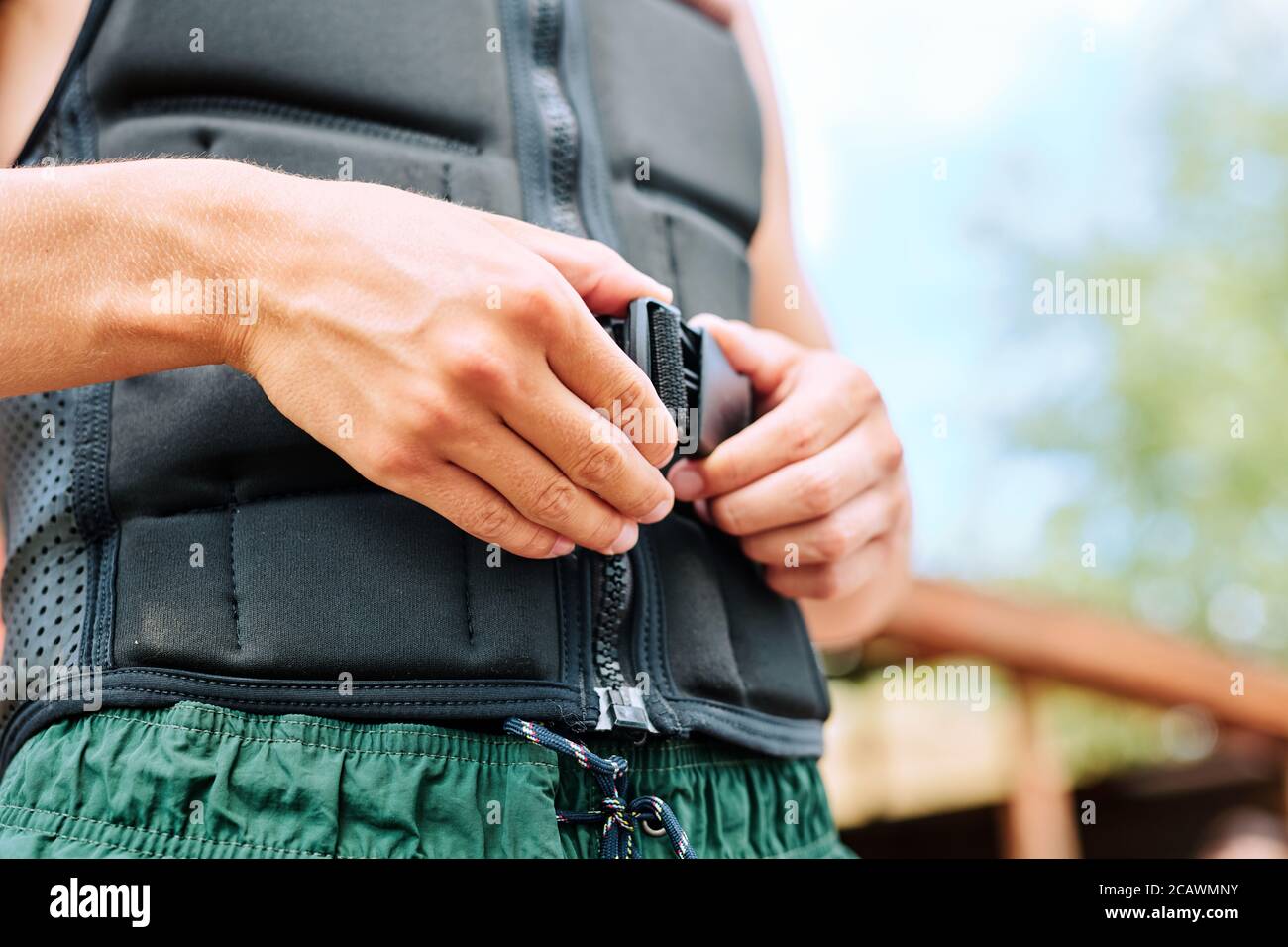 Les mains d'un jeune sportif bouchant la ceinture de sécurité à la taille de veste de sport noire Banque D'Images