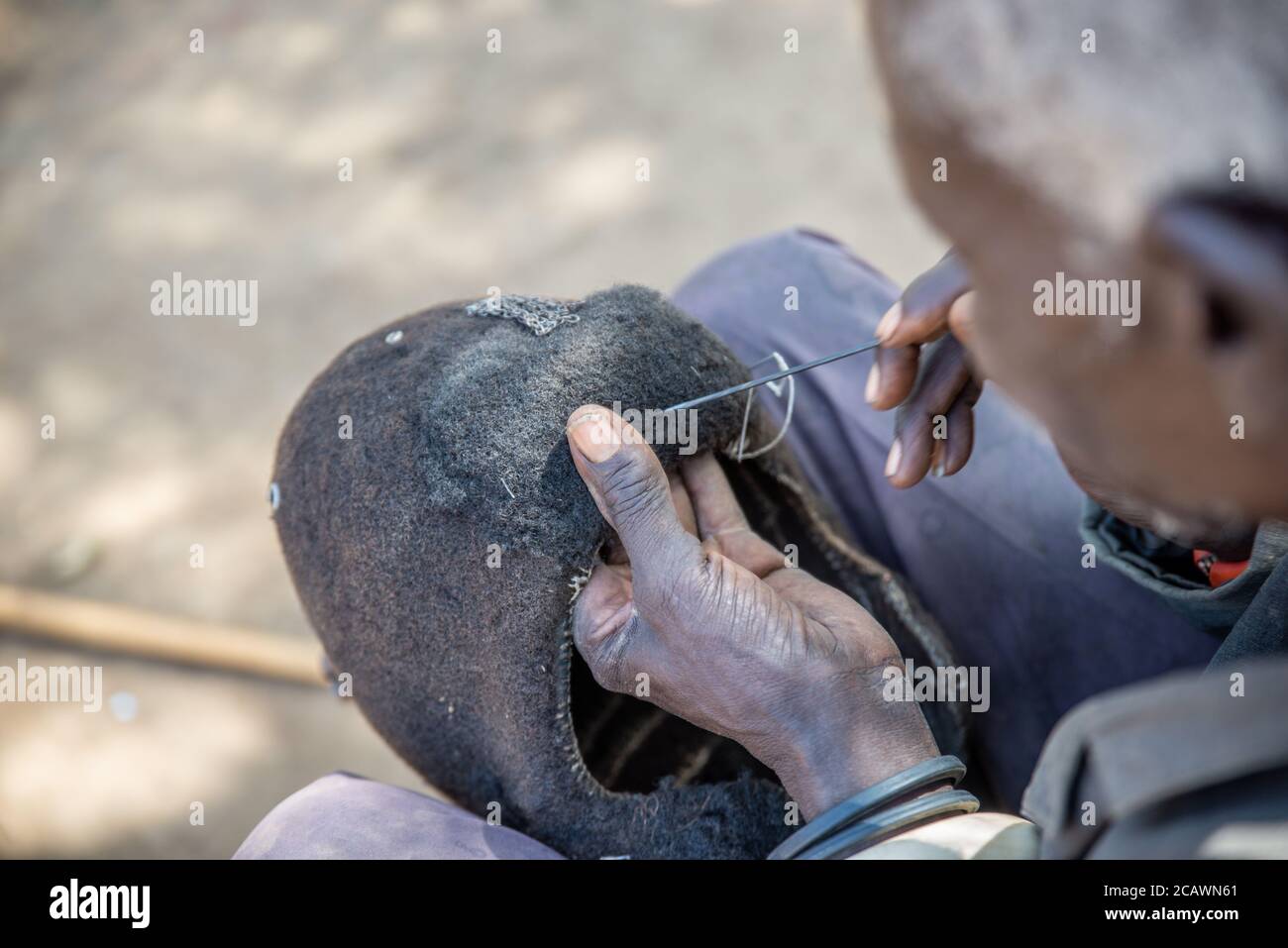 Ancien homme de Karamojong maintenant un étimat (epukot) hdeaddress fait de cheveux humains et de plumes d'autruche, district de Moroto, Ouganda Banque D'Images