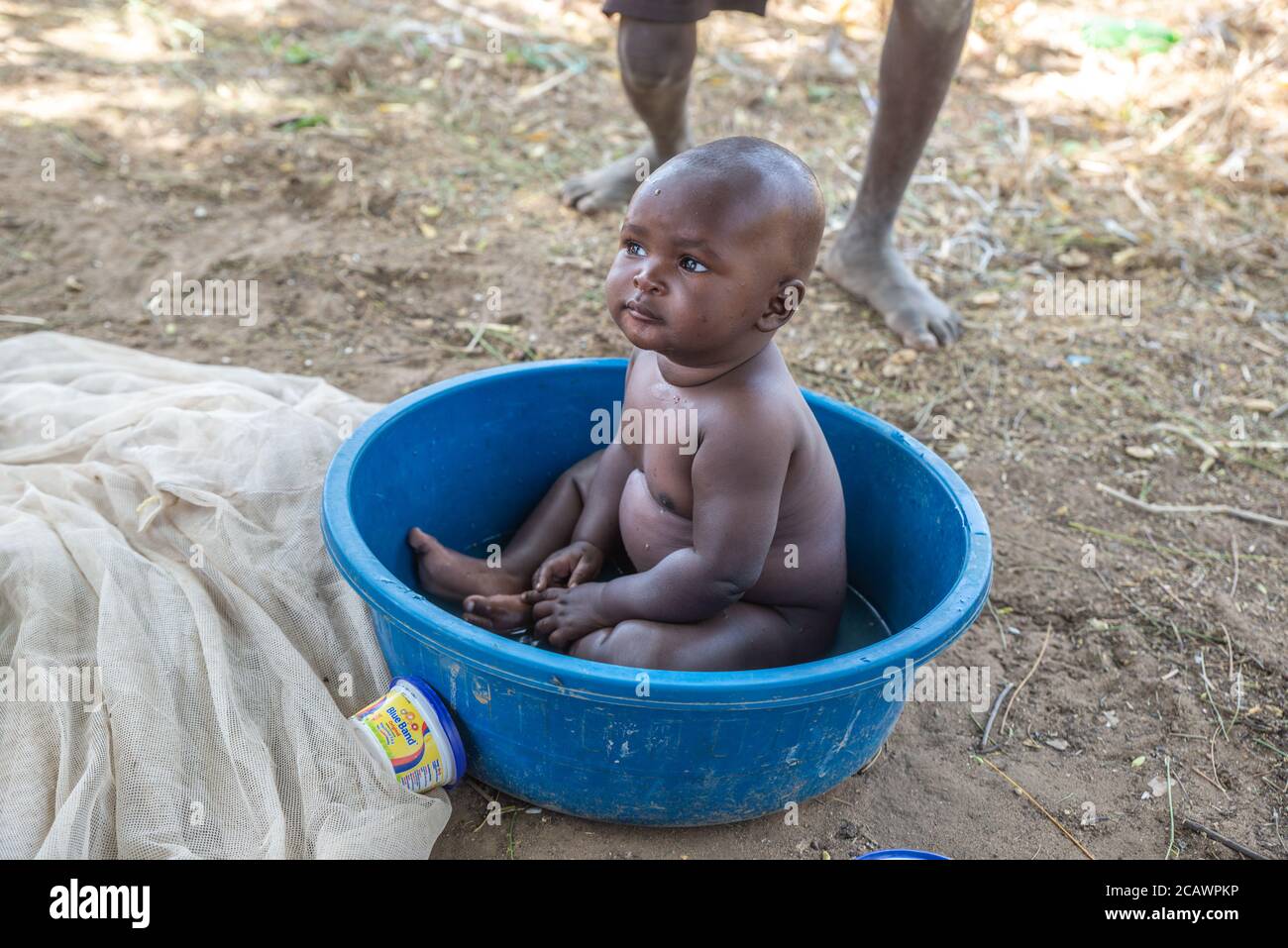 Un enfant de Karamojong dans un bassin bleu dans un village rural, district de Moroto, Ouganda Banque D'Images