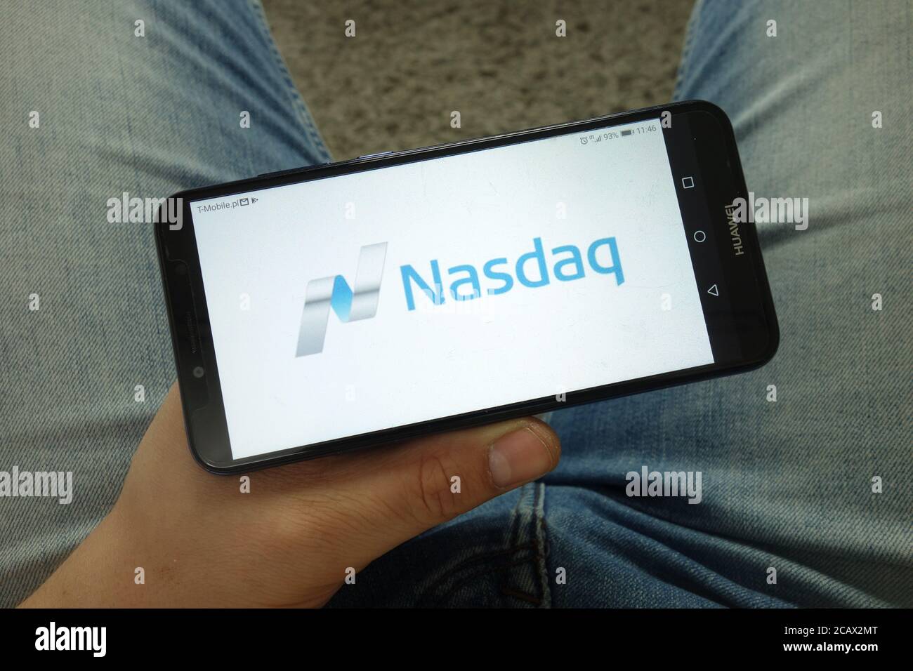 Homme tenant un smartphone avec le logo Nasdaq, Inc Banque D'Images