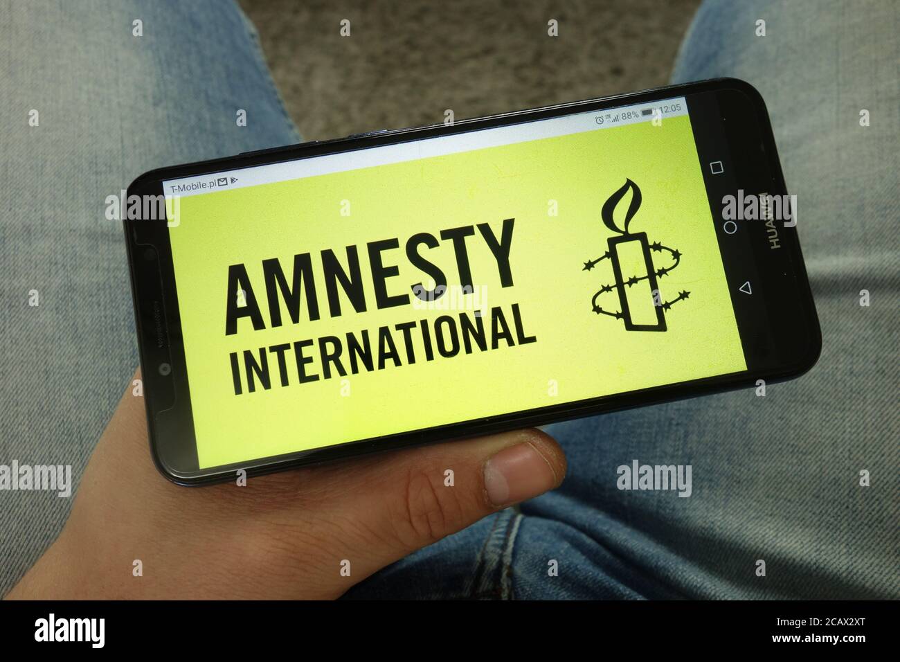 Homme tenant un smartphone avec le logo d'une organisation d'Amnesty International Banque D'Images