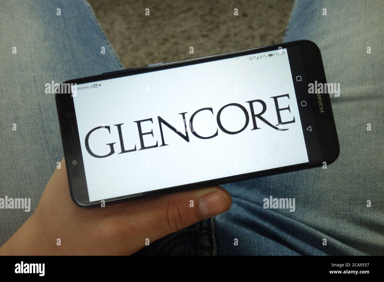 Homme tenant un smartphone portant le logo de la société Glencore plc Banque D'Images