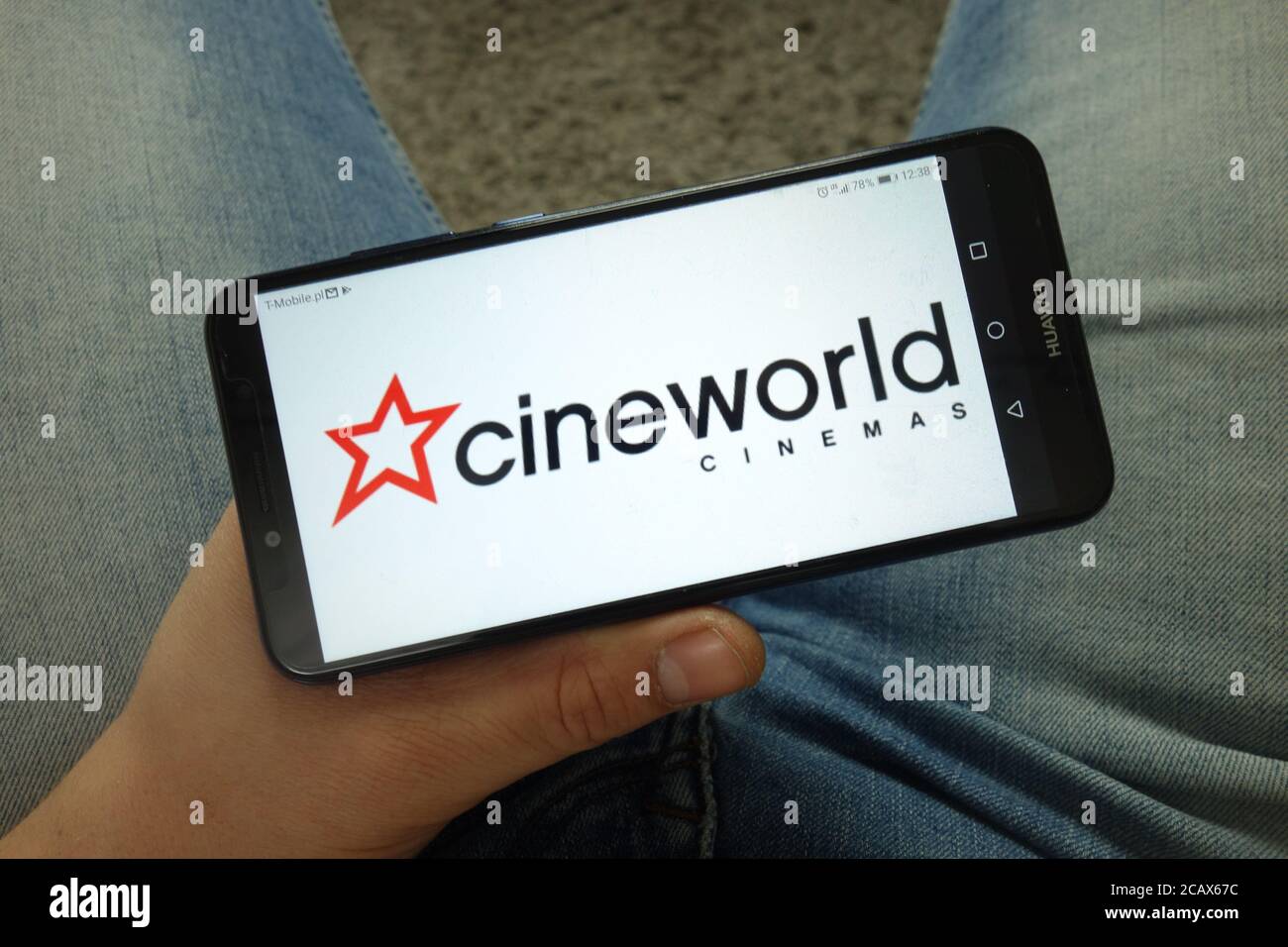 Homme tenant un smartphone portant le logo de Cineworld Group plc Banque D'Images