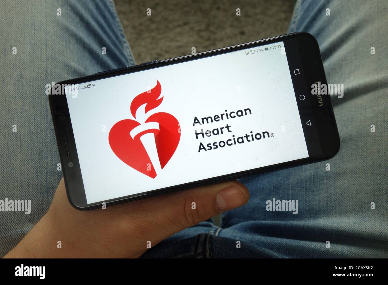 Homme tenant un smartphone avec le logo de l'American Heart Association (AHA) Banque D'Images