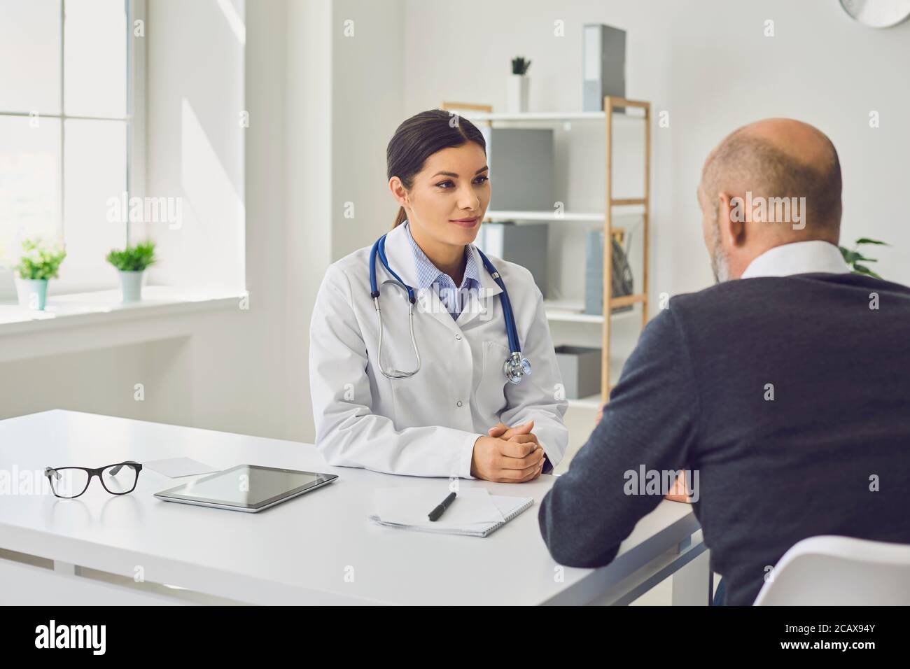Une femme médecin rédigeant une commande de médicaments pour un patient senior en clinique. Homme âgé en visite chez son prestataire de soins de santé Banque D'Images