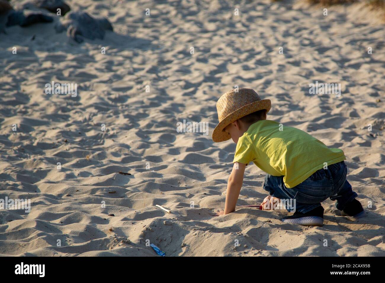 Un petit garçon jouant dans un bac à sable dans un parc en été Banque D'Images