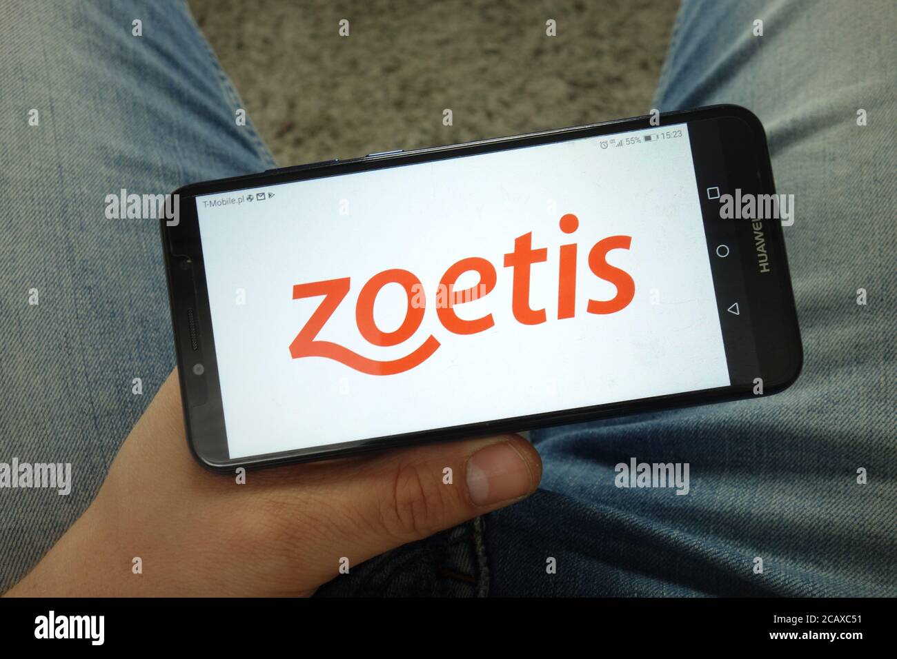 Homme tenant un smartphone avec le logo Zoetis Inc Banque D'Images