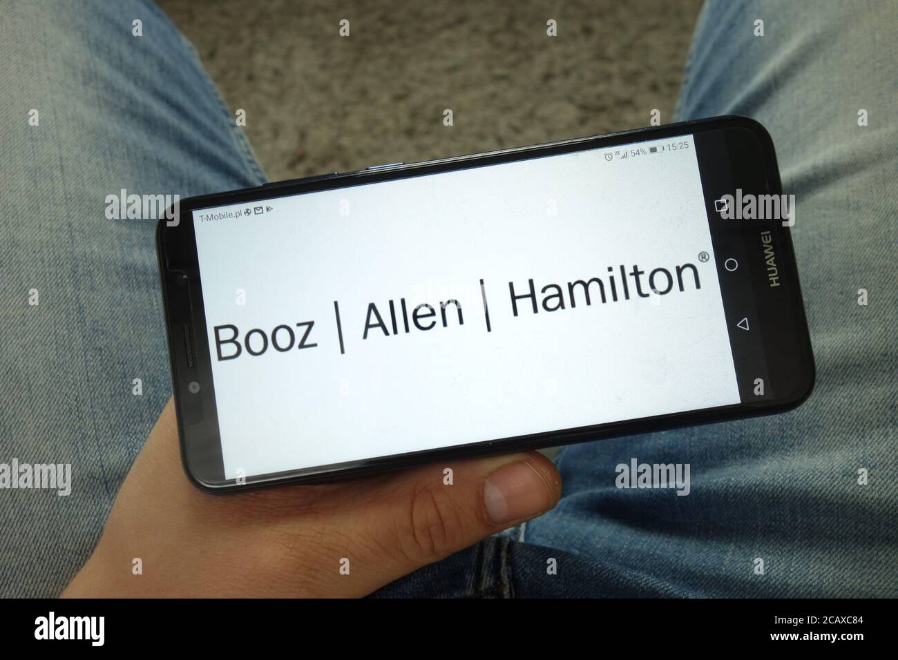 Homme tenant un smartphone avec le logo Booz Allen Hamilton Holding Corporation Banque D'Images