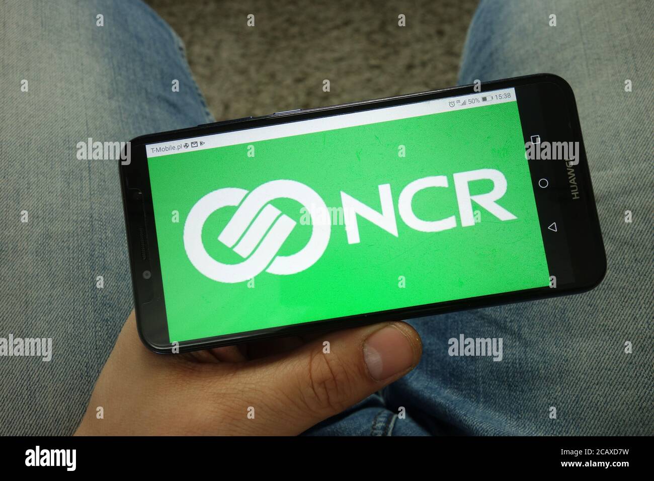 Homme tenant un smartphone avec le logo de NCR Corporation Banque D'Images