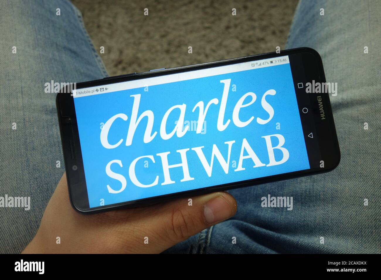 Homme tenant un smartphone avec le logo Charles Schwab Corporation Banque D'Images