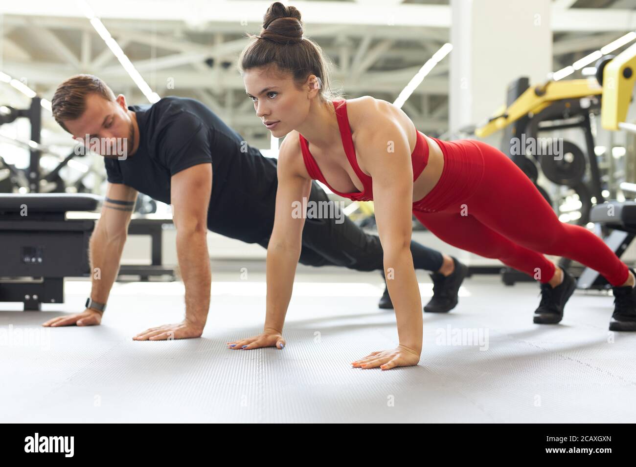 magnifique jeune couple fort qui fait des push-up ensemble dans la salle de gym. vue latérale Banque D'Images