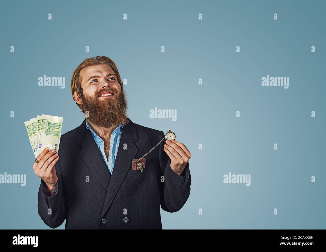 Portrait d'un homme d'hipster barbu adultes homme gai poings pompage isolés au studio bleu wall background looking up hol Banque D'Images