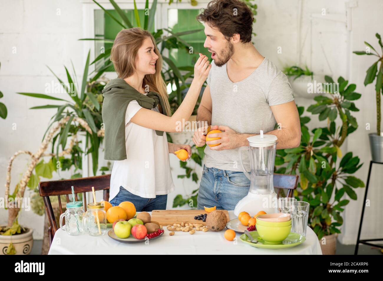 belle fille aux cheveux justes donnant une orange à son beau petit ami barbu dans la cuisine. photo de gros plan. fille traite son petit ami avec un fruit Banque D'Images