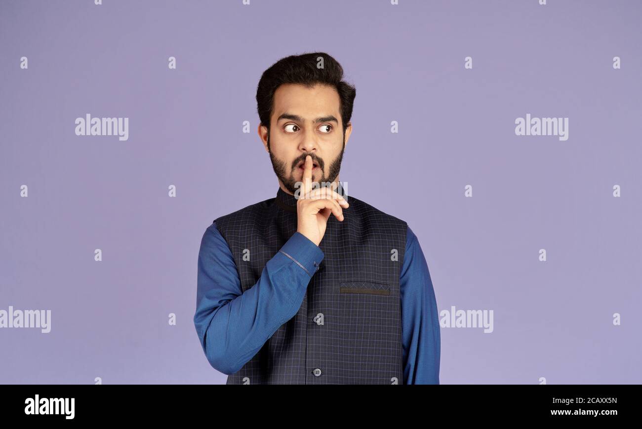 Homme indien attrayant montrant le geste de silence sur fond lilas Banque D'Images