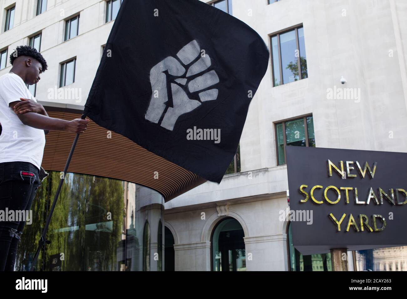 Londres Royaume-Uni 9 août 2020 l'étudiant de Tirek Morris 21 détient un drapeau avec le symbole du poing de pouvoir lors d'une manifestation Black Lives Matter à l'extérieur de Scotland Yard. Les manifestants appellent à la fin de la « surpolice des communautés noires » et à l’utilisation excessive de la force et des démarcheurs. Credit: Thabo Jaiyesimi/Alay Live News Banque D'Images