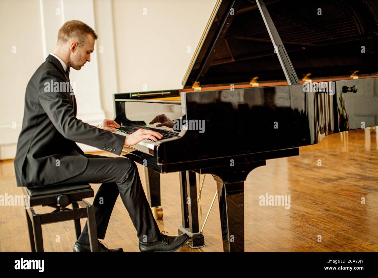 jeune homme caucasien élégant en costume élégant et formel, joue avec élégance au piano. un pianiste professionnel joue de la musique classique Banque D'Images
