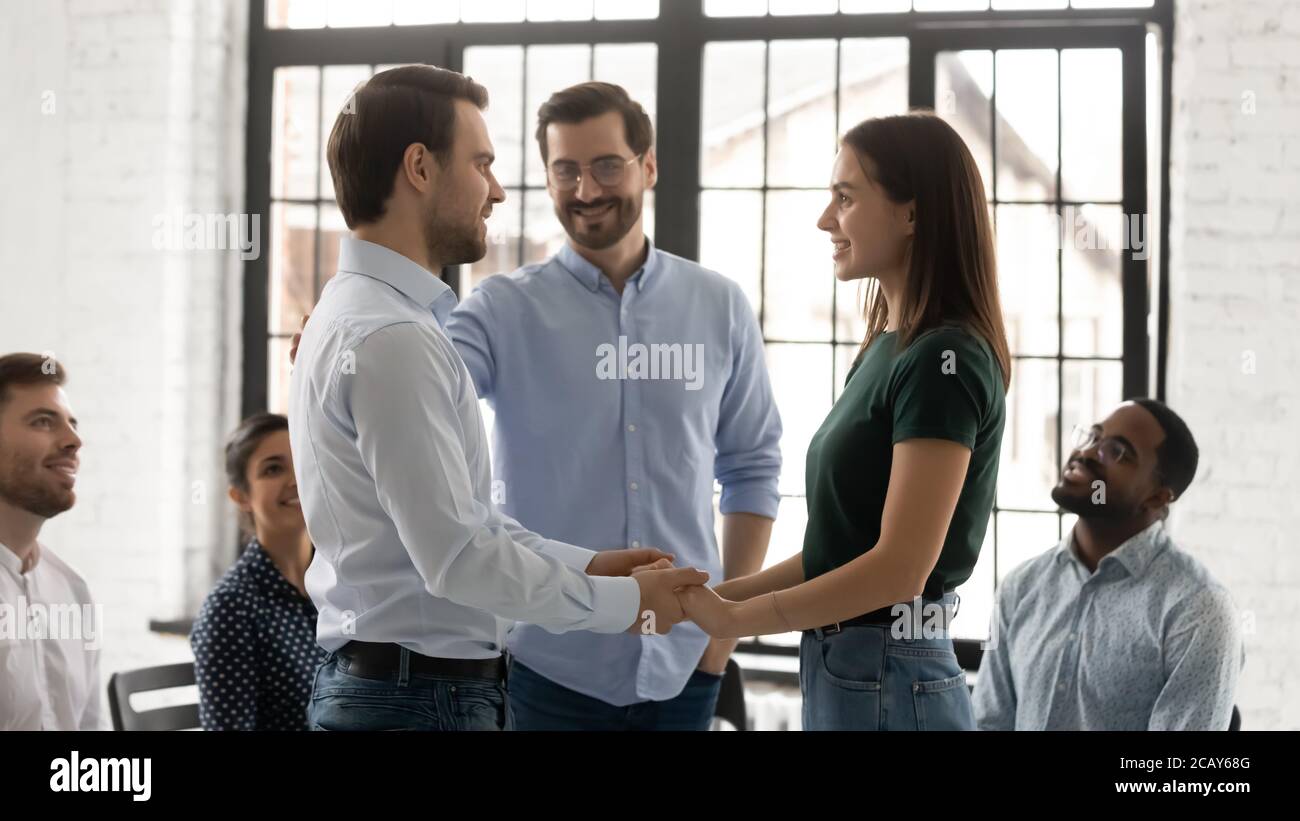 Un jeune couple heureux et réconcilié tient la main lors d'une séance de conseil en groupe Banque D'Images