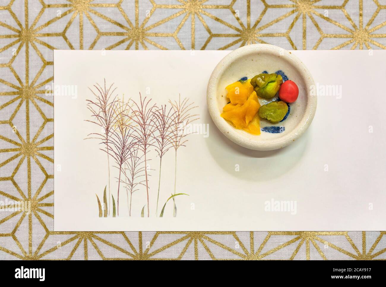 Légumes tsukemono fermentés japonais comme le ramish de takuan daikon, le concombre ou la prune de karikari-koume sur un tapis avec un dessin de sususuki et un Banque D'Images
