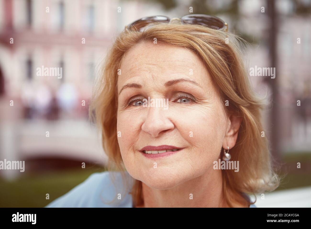 Portrait de la charmante et joyeuse femme blanche de race blanche d'environ 60 ans dans le centre-ville. Femme âgée attrayante pose à l'extérieur. Banque D'Images