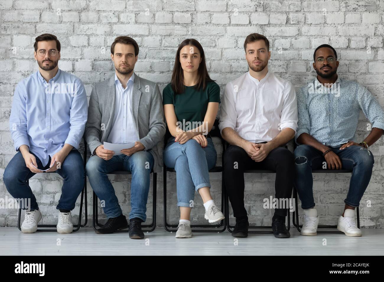 Portrait confiant divers candidats assis dans la rangée, en attente de l'entrevue Banque D'Images